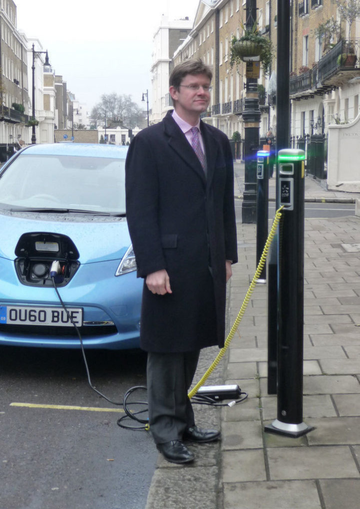 Member of UK government standing by an electric vehicle charging